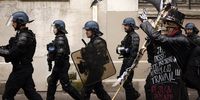 French police officers pass by a disguised protester carrying a scythe reading 'violence is the state' as thousands of people participate in a new demonstration against the government's reform of the pension system in Paris, France, 15 March 2023. Protests continue across the country due to the French government's plan to raise retirement age from 62 to 64 by 2030. On 09 March, a majority of senators validated the increasing of the legal retirement age to 64 years, the final adoption of the reform could take place on 16 March at the parliament.  EPA-EFE/YOAN VALAT