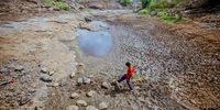 NASHIK, INDIA - MAY 26: A man crosses the dry and cracked bed of the Koparli dam on May 26, 2023 in Peth Taluka village, Nashik, Maharashtra, India. The Indian state of Maharashtra is facing a water crisis of unprecedented scale. Severe drought has taken hold over the inland parts of the state over the last few years; river currents have ebbed. There is less than 10% water available in 13 important reservoirs that supply the state, which is the powerhouse of the Indian economy, local media reports said. Environmental assessments have underscored concerns over the long-term availability of water. A Record number of tankers are the only source of water in large parts of state at present, barely keeping communities heavily reliant on predictable weather patterns for their livelihoods. (Photo by Ritesh Shukla/Getty Images)