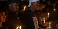 Ali Gule (white cap), of the Organisation Undoing Tax Abuse, and others during a candlelight ceremony, held outside Babita Deokaran’s Winchester Hills home, south of Johannesburg, where she was killed a year ago. (Photo: Shiraaz Mohamed)