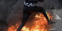 A protester jumps over a fire during a rally against the government's pension reform in Paris, France, 28 March 2023. France faces an ongoing national strike against the government's pensions reform after tthe French prime minister announced on 16 March 2023 the use of Article 49 paragraph 3 (49.3) of the French Constitution to have the text on the controversial pension reform law - raising retirement age from 62 to 64 - be definitively adopted without a vote.  EPA-EFE/CHRISTOPHE PETIT TESSON