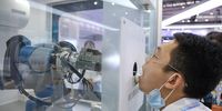 BEIJING, CHINA - AUGUST 18: A staff member takes part in a demonstration of a robot arm collecting swab samples for coronavirus disease (COVID-19) detection during the 2022 World Robot Conference at Beijing Etrong International Exhibition on August 18, 2022 in Beijing, China. The 2022 World Robot Conference kicked off on Thursday in Beijing. (Photo by Lintao Zhang/Getty Images)