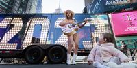 epaselect epa10375010 Robert Burck, better known as the busker 'The Naked Cowboy,' sings to a little girl sitting in front of the giant numerals used for the city's annual New Year's celebration which are on display for people to see in Times Square in New York, New York, USA, 20 December 2022.  EPA-EFE/JUSTIN LANE