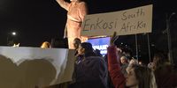 People raise flags and placards in the occupied West Bank city of Ramallah on 10 January 2024 as they gather around a statue of late South African president Nelson Mandela to celebrate the landmark genocide case filed by South Africa against Israel at the International Court of Justice. (Photo: Marco Longari / AFP)