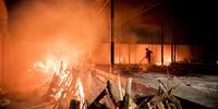 NEW DELHI, INDIA - APRIL 29: Workers can be seen at a crematorium where multiple funeral pyres are burning for patients who lost their lives to Covid-19 on April 29, 2021 in New Delhi, India. With recorded cases crossing 380,000 a day and 3000 deaths in the last 24 hours, India has more than 2 million active cases of Covid-19, the second-highest number in the world after the U.S. A new wave of the pandemic has totally overwhelmed the country's healthcare services and has caused crematoriums to operate day and night as the number of victims continues to spiral out of control. (Photo by Anindito Mukherjee/Getty Images)