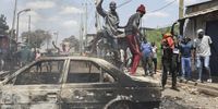 Protesters and supporters of the opposition Azimio coalition shout slogans while standing on a burnt out car and throw stones as they engage with riot police in running battles, during the second day of renewed nationwide protests in Nairobi, Kenya, 20 July 2023. Fresh nation-wide protests against the Kenyan government have been called by the Opposition coalition Azimio led by their opposition leader Raila Odinga, over high cost of living and new tax increases, that have been termed as punitive despite a court order stopping its implementations.  EPA-EFE/Daniel Irungu