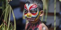 A child prepares for with his body and face painted as he  prepares to attend the sacred Ngerebeg ritual at the Tegallalang village in Gianyar, Bali, Indonesia, 03 April 2024. The sacred Ngerebeg ritual takes place every six months and it is mainly aimed at driving all evil spirits out of the villages. During the ritual, the participants paint their bodies in various colors and patterns to join the procession across the village.  EPA-EFE/MADE NAGI