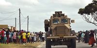 A soldier watches as crowds gather for food parcels in Zwide, Port Elizabeth. (Photo: Mike Holmes)
