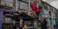 MANILA, PHILIPPINES - SEPTEMBER 17: Funeral workers load a body bag with the remains of Aljon Deparine, a victim of an alleged vigilante killing five years ago, which was exhumed after the lease on his tomb expired at a public cemetery on September 17, 2021 in Navotas, Metro Manila, Philippines. Relatives witnessed as workers hammered down tombs and pulled out the unrecognizeable remains of their loved ones, who were killed five years ago during President Duterte's bloody war on drugs. The families, too poor to renew the leases on their loved-ones graves, received assistance from a Catholic charity to have the remains cremated instead. President Duterte's government announced that it will not cooperate with the International Criminal Court's probe into his brutal anti-drug campaign, nor allow any investigators into the country. Judges at the ICC announced it was conducting a formal investigation into Duterte's drug war, which human rights groups estimate have claimed the lives of more than 30,000 mostly poor people, by police in controversial anti-drugs operations or by vigilantes allegedly with the backing of the police. (Photo by Ezra Acayan/Getty Images)