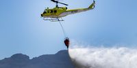 A helicopter carries water to demonstrate firefighting procedures heading into South Africa’s most threatening fire season in eight years. (Photo: Kyra Wilkinson)