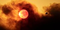 GOLETA, CA - OCTOBER 13: A firefighting helicopter flies as smoke from the Alisal Fire shrouds the sun on October 13, 2021 near Goleta, California. Pushed by high winds, the Alisal Fire grew to 6,000 acres overnight, shutting down the much-traveled 101 Freeway along the Pacific Coast. (Photo by David McNew/Getty Images)