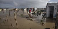 A woman collects her belongings from her  flooded home in  Covid-19 informal settlement in Bloekombos on 1 July 2021 in Cape Town, South Africa. It is reported that heavy rains and floods have battered some parts of the Western Cape and informal settlements in the area have been adversely impacted. (Photo by Gallo Images/Brenton Geach)