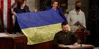 WASHINGTON, DC - DECEMBER 21: U.S. Speaker of the House Nancy Pelosi (D-CA) and Vice President Kamala Harris hold a Ukrainian flag signed by members of the that country's military given to them by President of Ukraine Volodymyr Zelensky as he addresses a joint meeting of Congress in the House Chamber of the U.S. Capitol on December 21, 2022 in Washington, DC. In his first known trip outside of Ukraine since Russia invaded, Zelensky met with U.S. President Joe Biden and outlined Ukraine's request for continued military aid. (Photo by Chip Somodevilla/Getty Images)