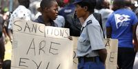 A ruling Zimbabwe African National Union Patriotic Front (Zanu-PF) supporter holds a placard calling for the lifting of sanctions outside parliament in Harare on 1 October 2019. (Photo: EPA-EFE / Aaron Ufumeli)