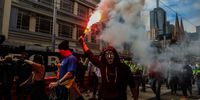 MELBOURNE, AUSTRALIA - SEPTEMBER 21: Protestors are seen marching as a flare is lit as thousands march through Melbourne after State Government announces construction shutdown on September 21, 2021 in Melbourne, Australia. Protests started outside the headquarters of the Construction, Forestry, Maritime, Mining and Energy Union (CFMEU) in Melbourne on Monday over the introduction of mandatory vaccinations for construction workers. The Victorian government has announced a two-week shutdown of construction after violence broke out on Monday with riot police using rubber bullets to disperse the crowd. The protest comes after the state government announced that all construction workers would need to receive at least one dose of a COVID-19 vaccine by September 23 to be able to continue working. Melbourne is currently subject to COVID-19 lockdown restrictions, with people only permitted to leave home for essential reasons.  (Photo by Asanka Ratnayake/Getty Images)
