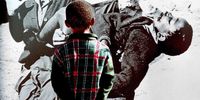 16 June 2002. Enoch Sitole(6) from Soweto admires the famous photograph taken by Sam Nzima of Hector Petersen at the Memorial site in Soweto on Youth Day. South Africa.