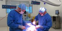 Dr Landau, left, and Dr Kairinos, raise a skin and tissue flap to cover a huge bedsore on the side of the patient’s thigh. (Photo: Elsabé Brits)