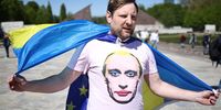 A Russian opposition activist of Demokrati-JA with a Ukrainian and a t-shirt depicting the face of Russian President Vladimir Putin walks  during Victory Day commemorations at the Soviet World War II memorial at Treptow park in Berlin, Germany, 09 May 2023. World War II in Europe ended with the unconditional surrender of Nazi Germany on all fronts on 09 May 1945.  EPA-EFE/CLEMENS BILAN