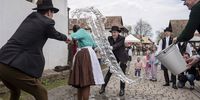 Dressed in folk costumes, young men pour water on a young woman in Holloko, a mountain village enlisted on the World Heritage List of Unesco, some 80 kms northeast of Budapest, Hungary, 10 April 2023. According to an old Hungarian tradition, on Easter Monday young men pour water on young women, who in exchange present their sprinklers with hand-decorated coloured eggs.  EPA-EFE/Peter Komka HUNGARY OUT