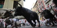 PAMPLONA, SPAIN - JULY 09: Two runners fall in front of charging fighting bulls at the Mercaderes curve during the third San Fermin running of the bulls on July 9, 2008 in Pamplona, Spain. Fighting bulls are run through the historic heart of Pamplona for eight days in this fiesta made famous by the 1926 novel of U.S. writer Ernest Hemmingway called 'The Sun Also Rises'.  (Photo by Denis Doyle/Getty Images)
