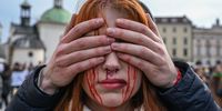 KRAKOW, POLAND - APRIL 09:  A man covers the eyes of a Ukrainian woman painted in blood colors as they take take part in a silent protest against the mass killing of Ukrainian civilians by the Russian army during the invasion of Ukraine on April 09, 2022 in Krakow, Poland. Protestors staged a protest accusing Russia of genocide as the numbers of confirmed civilian dead in towns north of Kyiv like Bucha, Irpin and Hostomel are continuing to rise in the wake of the Russian military retreat following their occupation of the area.  (Photo by Omar Marques/Getty Images)