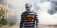 epa10473043 A Palestinian protester seeks cover from tear gas fired by Israeli troops during clashes after a demonstration against Israel's settlements on the lands of Kafr Qaddum village, near the West Bank city of Nablus, 17 February 2023.  EPA-EFE/ALAA BADARNEH