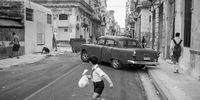 "Havana Running Away". This is the third picture of thousands taken over a month-long trip to Havana, Cuba, with my 35mm – and it is my favourite! There is something happening here, some kind of tension: this car looks like it is drifting in the middle of the street, and this kid looks like he is running away from something. © Etienne Souchon, France, Winner, Open, Street Photography, 2022 Sony World Photography Awards