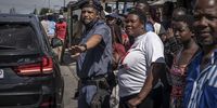 A Colonel Ryland of the SAPS Tactical Response Team keeps back the crowd as Police Minister Bheki Cele and his delegation make their way out of Diepsloot. (Photo: Shiraaz Mohamed)