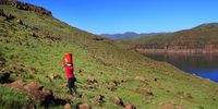 Lindiwe Hloaele in the middle of her journey home to Thabaneng village, mounting a rocky slope with 25 litres of water on her head. (Photo: Sechaba Mokhethi)