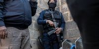 An armed police officer stands on guard in the Jumpers settlement in Cleveland, Johannesburg, the site of a mass shooting