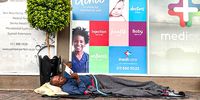 James, from Durban., reading on a pavement in Linden, Johannesburg, partner to Pitso and Lesedi, says he prefers reading to drinking. He had done a gardening job the day before. (Photo: Angus Begg)