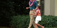 US President Barack Obama dances while walking out of the Oval Office with his daughter Sasha, 8, to join a luau for members of Congress and their families on the South Lawn of the White House June 25, 2009 in Washington, DC. In a celebration of the president's home state, the South Lawn was decorated with tiki torches and palm huts and the meal prepared by famous Hawaiian chef Alan Wong. (Photo by Chip Somodevilla/Getty Images)