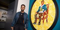 LONDON, ENGLAND - OCTOBER 04: In this image released on October 4th, Melissa Thompson poses beside Kehinde Wiley's painting, 'Portrait of Melissa Thompson' (2020) at The V&amp;A on October 04, 2021 in London, England. The monumental two-metre oil painting was made as part of Wiley's series The Yellow Wallpaper, and depicts Melissa Thompson, a young woman the artist met at Ridley Road market in Dalston, East London. The background features a repeating floral motif inspired by William Morris's 'White Tulip' wallpaper design – an artist and designer long associated with and collected by the V&amp;A. From today until 2024, the painting can be seen in the V&amp;A's William Morris Room (gallery 125) alongside the William Morris-designed wallpaper that inspired it. It will then move to its new, permanent home at V&amp;A East Museum, which opens in 2025. (Photo by Tim P. Whitby/Getty Images for V&amp;A)
