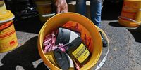 Emile Abrahams shows a full collection bucket at the TB HIV Care mobile syringe &amp; needle exchange in Wynberg, one of more than forty buckets the NGO collects from sites around the city every week, 15 Ocotber 2024. (Photo: David Harrison)