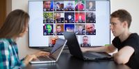 Artem Kuharenko, co-founder of NTechLab, right, works on a laptop computer as the faces of individuals identified by the FindFace facial recognition app sit on a digital screen at the company's offices in Moscow, Russia, on Tuesday, July 12, 2016. FindFace, which has been downloaded for free more than a million times on both Apple and Android platforms since February, allows users to identify strangers at the click of their smartphone cameras as long as long as theyve been previously identified in one of more than 250 million photos posted on VKontakte, or VK, Russias answer to Facebook. Photographer: Andrey Rudakov/Bloomberg via Getty Images