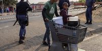 Westbury area walk through a police checkpoint with a shopping trolley carrying water containers during a protest demanding that their water supply be restored, in Johannesburg, South Africa, 10 September 2025. Following two weeks without water, Westbury residents have taken to the streets to try to get their water supply switched on after a number of issues have plagued the city's water supply. Significant water infrastructure issues in the city have resulted from years of mismanagement by the ruling ANC (African National Congress) and have led to the situation in this area and others in the country's biggest city.  EPA/Kim Ludbrook