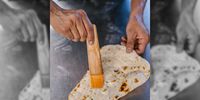 Munir Sheikh brushes naan with garlic butter. (Photo: Naomi Campbell)<br>