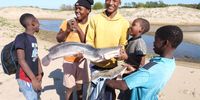 This group of youngsters used their hands to scoop up barbel and other fish that washed out of the lake mouth last week. (Photo: Ezemvelo)