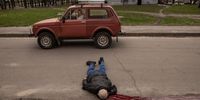 KHARKIV, UKRAINE - APRIL 19: (EDITORS NOTE: This image contains graphic content) A man looks out the window of his car as he drives past the body of a civilian killed during heavy Russian shelling of a residential neighbourhood on April 19, 2022 in Kharkiv, Ukraine. According to preliminary reports four people were killed and 21 injured in the bombardment. Russia began the “next phase” of its military offensive into eastern Ukraine with intensified missile attacks, shelling, and tank movements across the countries eastern cities and towns.  (Photo by Chris McGrath/Getty Images)
