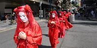 Members of the 'Red Rebels' take part in a Extinction Rebellion protest as they march in front of a giant animatronic puppet depicting a burning Koala called 'Blinky' pushed through the streets of the central business district (CBD) in Brisbane, Queensland, Australia, 15 March 2023. Extinction Rebellion (XR) environmental activists marched through the CBD of Brisbane to protest against the fossil fuel industry.  EPA-EFE/DARREN ENGLAND 