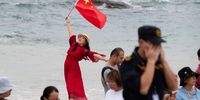 epa09166965 A woman holds up the Chinese national flag as people gather to watch the the launch of the Long March 5B rocket carrying China's Tianhe space station core module from the Wenchang Spacecraft Launch Site in Hainan Province, China, 29 April 2021. China launched into space the core module of its space station, marking the beginning of a series of launch missions to complete the space station by the end of next year.  EPA-EFE/MATJAZ TANCIC