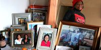 Linda Dewy looks at the collection of photographs on her dressing table at Ahmed Kathrada House in Green Point, Cape Town. 26 June 2025. (Photo: Tamsin Metelerkamp)
