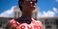WASHINGTON, DC - JUNE 25: An abortion-rights activist with the words Abort the Court painted on her chest protests in front of the Supreme Court building following the announcement to the Dobbs v Jackson Women's Health Organization ruling on June 25, 2022 in Washington, DC. The Court's decision in the Dobbs v Jackson Women's Health case overturns the landmark 50-year-old Roe v Wade case, removing a federal right to an abortion. (Photo by Nathan Howard/Getty Images)