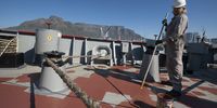 Framed by Table Mountain, able seaman Rodolfo Torres coats the Noosfera’s deck with primer. (Photo: Matrix Images / Nic Bothma)