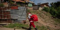 epaselect epa10370821 A man dressed as Santa Claus and carries a bag of gifts during the "A Toy, Good News" initiative, in the area of the General del Sur Cemetery in Caracas, Venezuela, 17 December 2022. A Santa Claus and several volunteers - most of them journalists - delivered gifts to 350 children from a Caracas community 17 December, thanks to donations from the union and individuals, during the initiative called "A toy, good news", which a group of press workers has been developing since 2017 with the aim of making children smile.  EPA-EFE/Rayner Pena R.