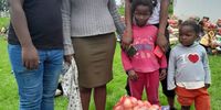 An SA Harvest team member gives a food<br>parcel to a recipient and her children in<br>Redoubt, Mbizana. (Photo: SA Harvest)