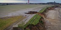 HAPPISBURGH, ENGLAND - JANUARY 27: A man walks his bicycle past a recent landslip on the cliff edge and beach in the village of Happisburgh on January 27, 2021 in Happisburgh, England.  Erosion of the Norfolk sandy cliffs and sand dunes has caused many buildings and farmland to be lost to the sea. The effects of global climate change causing storms and sea swells has seen the East Coast of the United Kingdom lose up to one metre of coast line each year.  (Photo by Christopher Furlong/Getty Images)