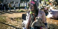 A homeless man carries his cup of warm soup as he holds a teddy bear at a feeding point organized by a local church group in Johannesburg, South Africa, 21 April 2020. (Photo: EPA-EFE/KIM LUDBROOK)