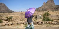 A woman shelters from the heat under an umbrella as she walks along a road on January 21, 2017 near Adigrat, Ethiopia. Guide book publisher Lonely Planet recently ranked Ethiopia among the top ten 2017 world tourist destinations. (Photo by Carl Court/Getty Images)