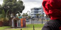 Linda Dewy stands outside her room at Ahmed Kathrada House, an occupied building in Green Point, Cape Town, and looks towards the Cape Wheel at the V&amp;A Waterfront. 26 June 2025. (Photo: Tamsin Metelerkamp)