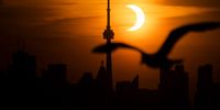 TORONTO, ON - JUNE 10: The sun rises behind the skyline during an annular eclipse on June 10, 2021 in Toronto, Canada. Across parts of Canada, viewers witnessed the rare sighting of a so-called "ring of fire" solar eclipse - a thin outer ring of the sun's disk that is not completely covered by the smaller dark disk of the moon. (Photo by Mark Blinch/Getty Images)
